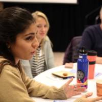 A student speaks to attendees at a round table discussion
